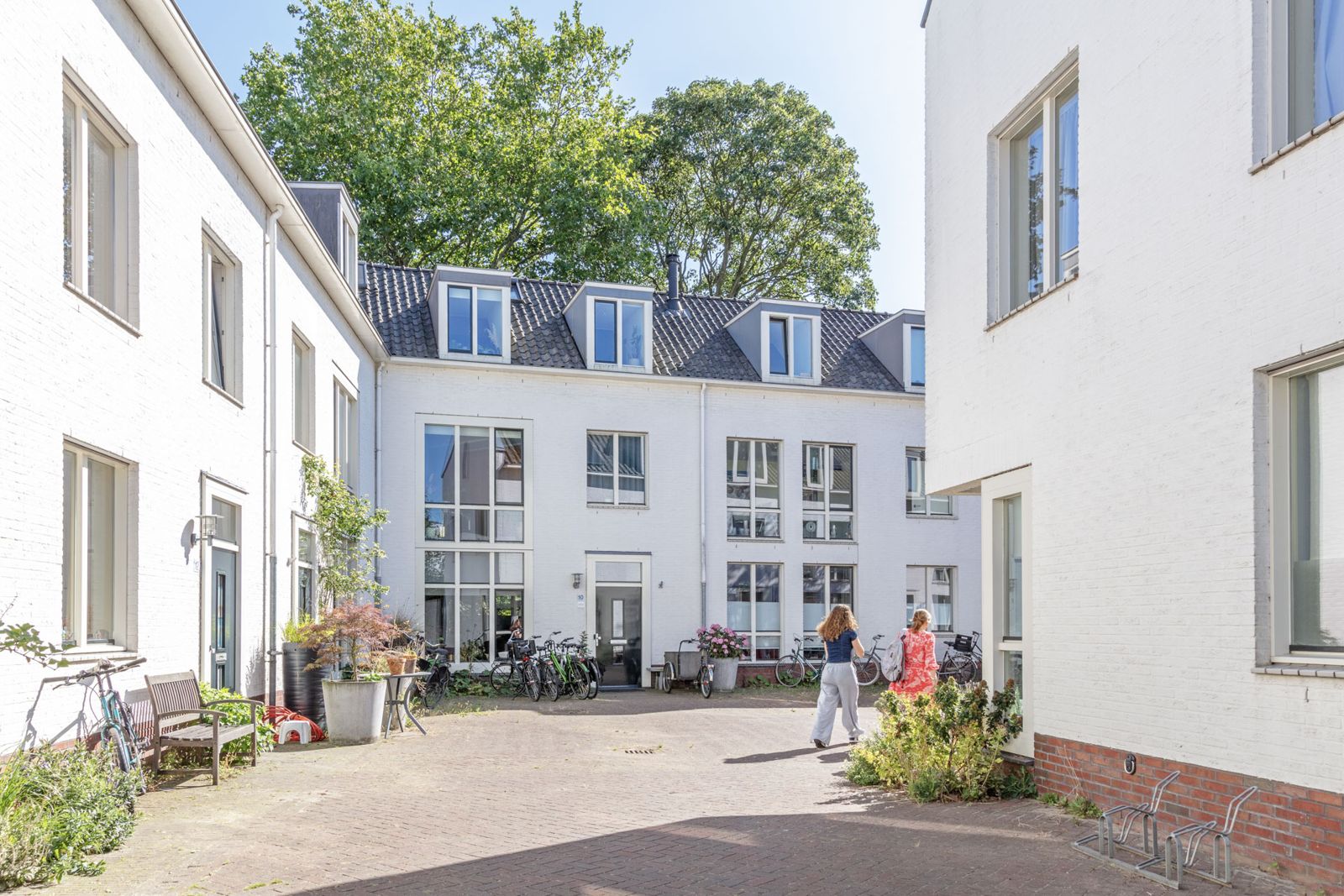 Witte gevels aan een van de pleinen, met fietsen, planten en een bankje
